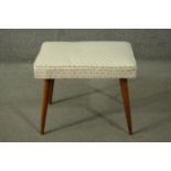 A circa 1960's teak stool, the seat upholstered in patterned white fabric, hinged, on tapering legs.