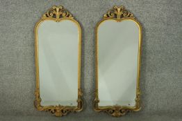 A pair of 20th century gilt mirrors, with a scrolling foliate crest, and a rope twist border, over a