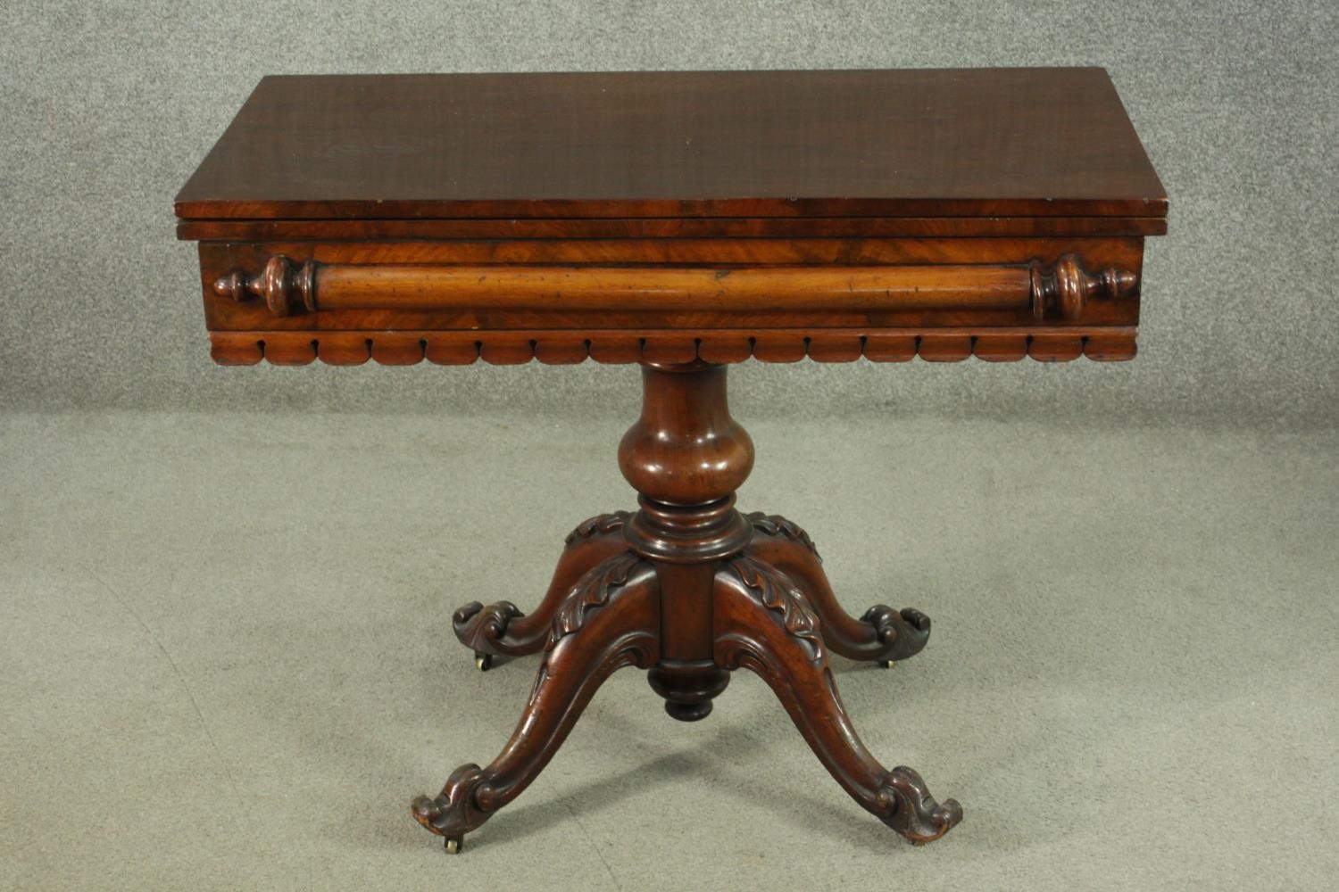 A Victorian figured walnut tea table, with a foldover top, over a baluster stem, on a quatraform
