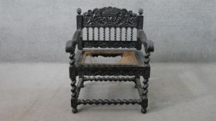 A Charles II style ebonised open armchair, with an ornately carved top rail over barley twist