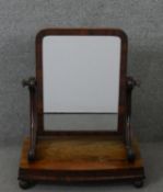 A William IV mahogany swing framed toilet mirror, the rectangular mirror on scrolling supports,