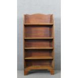 A George III pine waterfall style bookcase, with a shaped top, over four adjustable shelves, on