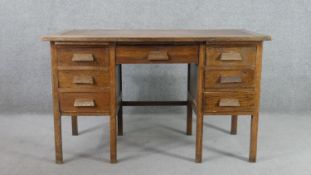 A circa 1940s oak utility furniture style desk, with an arrangement of nine drawers on square