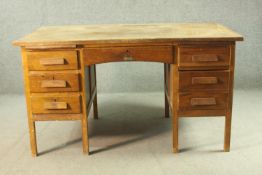 A circa 1940s oak desk, the rectangular top over two slides, and an arrangement of seven drawers