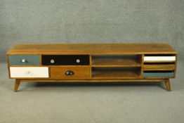 A contemporary mango wood sideboard or media cabinet, with an arrangement of seven drawers, some