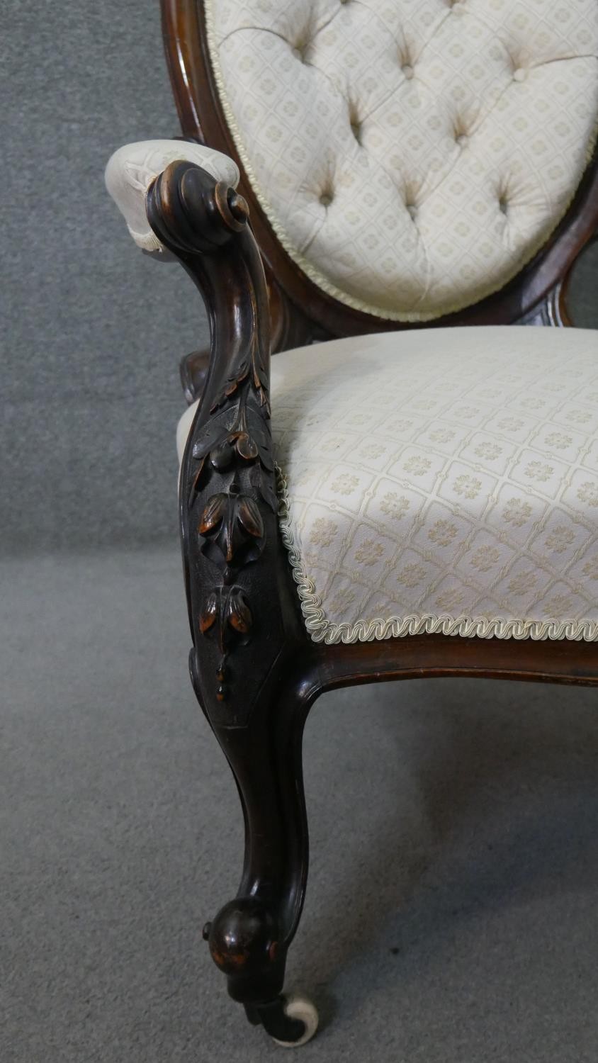 A Victorian walnut open armchair, upholstered in patterned ivory fabric, with an oval buttoned back, - Image 6 of 7