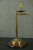 A vintage brass adjustable reading lamp, with an articulated arm and a cylindrical stem, on a