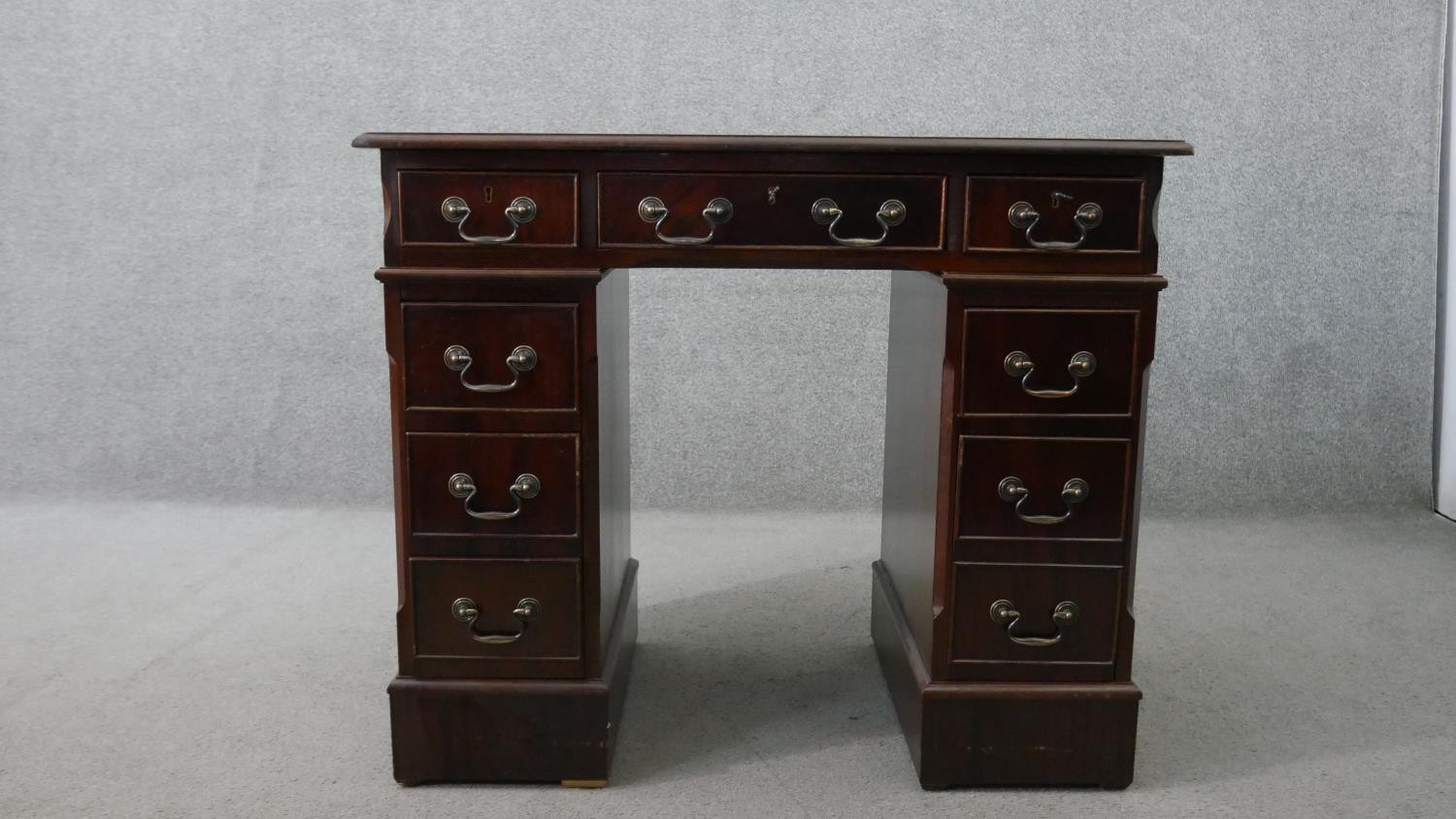 A 19th century style mahogany pedestal desk, of small proportions, with a tooled green leather