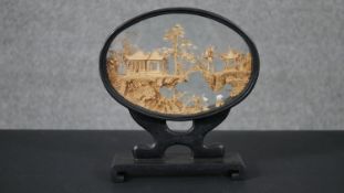 A Chinese carved cork diorama with temple, rocky outcrops, pine trees and storks, within an oval