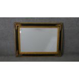 A French style ebonised and parcel gilt mirror, of rectangular form with a bevelled mirror plate.