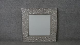 A contemporary stainless steel framed mirror, of square form, the frame cast with spherical