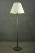 An ebonised standard lamp, with a cream shade, on a cylindrical stem, with a circular base. H.185cm.