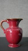 A vintage red glaze jug with twisted handle design with gilded detailing to the handles and starts