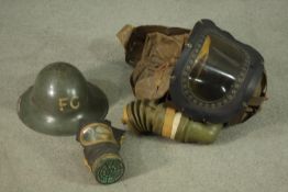 A WWII childs respirator with military issue gas mask and WWII helmet, stamped FG. H47 W.40cm. (
