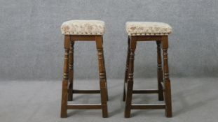 A pair of late 20th century stained beech bar stools, upholstered in a tapestry style fabric, on