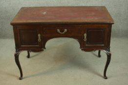 An Edwardian mahogany kneehole writing table, with a burgundy writing insert, over a central