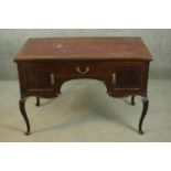 An Edwardian mahogany kneehole writing table, with a burgundy writing insert, over a central