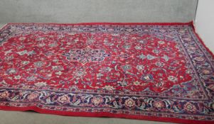 A handmade Persian Keshan carpet with central foliate medallion on a burgundy ground within