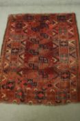 A hand woven Afghan rug with repeating geometric motifs on a burgundy ground. L.155 W.120cm.