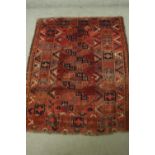 A hand woven Afghan rug with repeating geometric motifs on a burgundy ground. L.155 W.120cm.