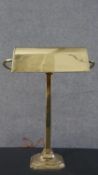 An early 20th century brass bankers lamp, with an adjustable shade on a square step down base. H.
