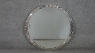 A contemporary circular wall mirror, with a bevelled mirror plate in a polished metal frame. Diam.