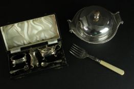 A silver plate cased cruet set along with a muffin fork and muffin warmer with scrolling form