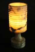 A circa 1970s light coloured onyx table lamp, of cylindrical form with a ribbed shade and base. H.26