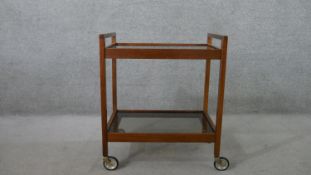 A circa 1960s mahogany drinks trolley, with two tiers of clear plate glass, on castors. H.72 W.62