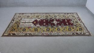 A Turkish Milas rug on a wine ground within stylised multiple borders. L.230 W.127cm