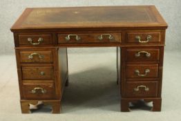 A walnut pedestal desk, with a tooled leather skiver over an arrangement of nine graduated