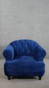 A contemporary Harto armchair, upholstered in blue suede style fabric, with a buttoned back, and