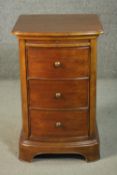 A Victorian style fruitwood bow front bedside chest, with a slide over three drawers, on a plinth