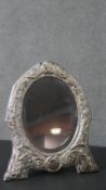 A silver repousse oval easel dressing mirror with foliate and floral design and blue velvet back.