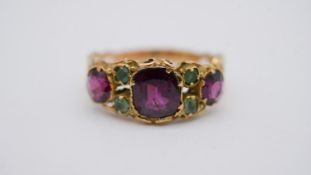 A Victorian yellow metal carved half hoop ring set with three cushion shape mixed cut garnets with a