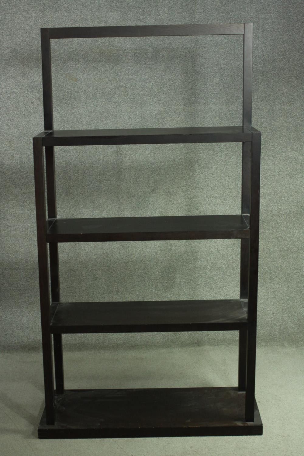 A contemporary ebonised oak shelving unit, with three shelves supported by square section