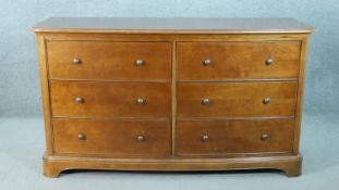 A Victorian style fruitwood bow front chest, with two banks of three drawers with knob handles, on a