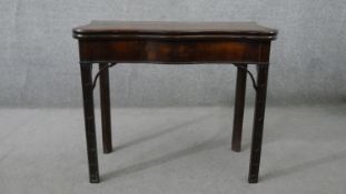 A late George II mahogany serpentine card table, the foldover table top lined with green baize,