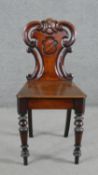 A Victorian mahogany hall chair, the carved and pierced scrolling back carved with a shield, over