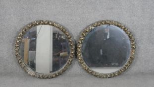 A pair of circular wall mirrors, with a moulded gilt frame decorated with ribbon tied embellishments