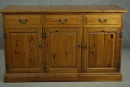 A late 20th century pine dresser base, with three short drawers over three cupboard doors, on a