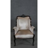 A circa 1900 mahogany armchair, with a carved crest, the scrolling arms, back and seat upholstered