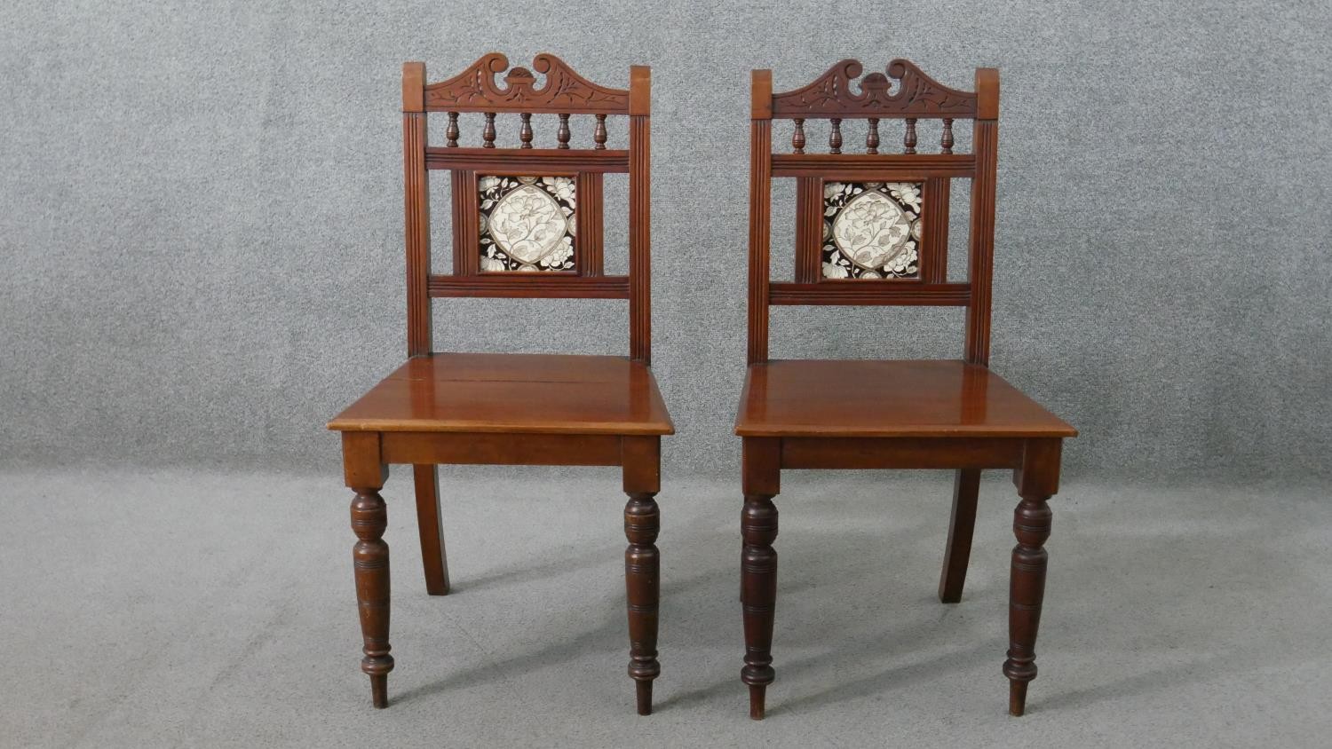 A pair of Victorian walnut Aesthetic movement hall chairs, the back set with a single tile, possibly