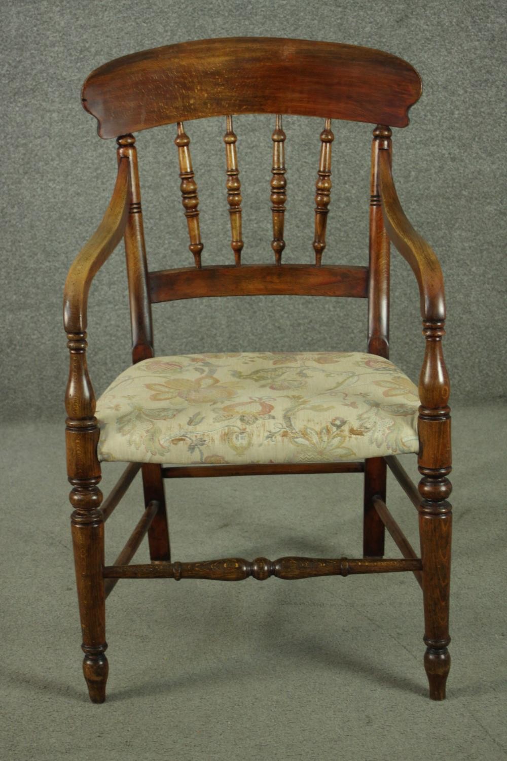 A rustic stained beech bar back open armchair, with turned spindles over a tapestry style seat, on