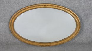 An oval gilt mirror, with a bevelled mirror plate, the frame with egg and dart and beaded borders.