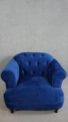 A contemporary Harto armchair, upholstered in blue suede style fabric, with a buttoned back, and