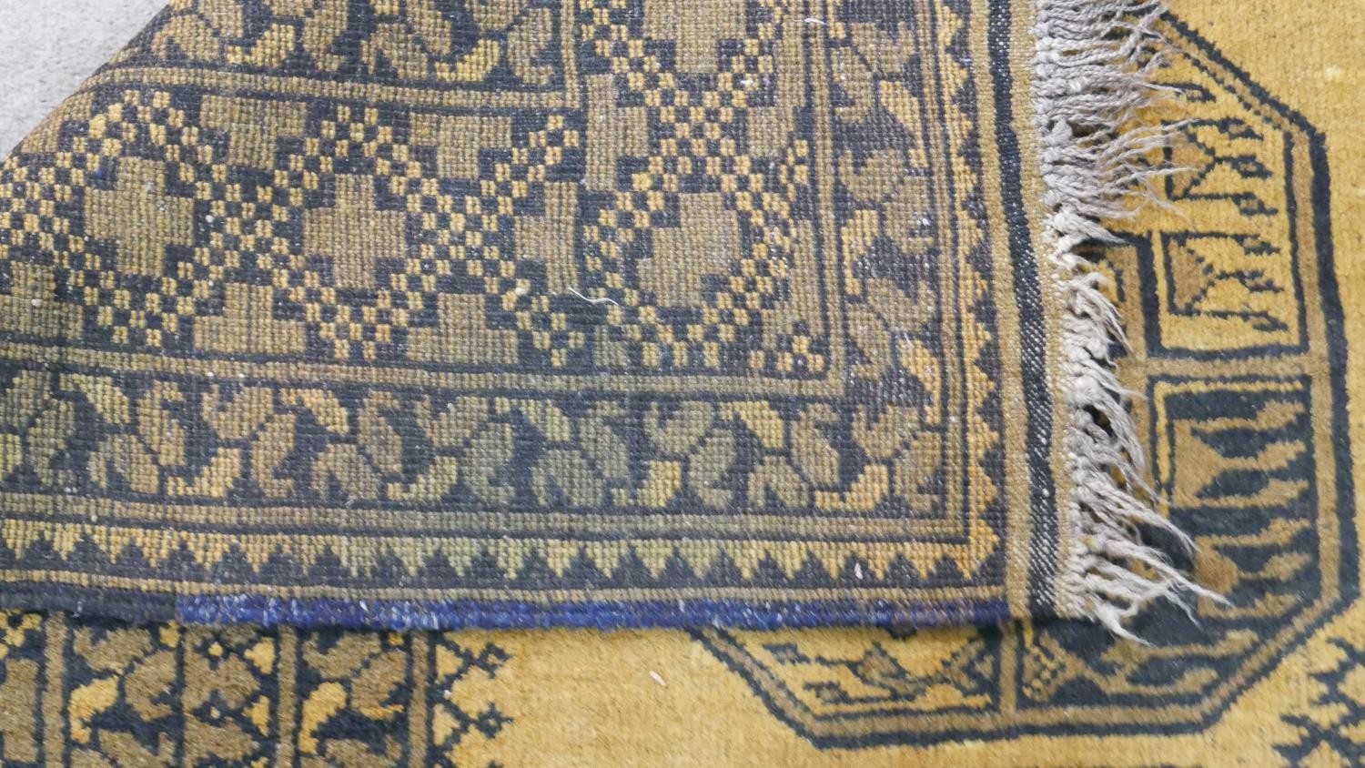 A hand made Afghan carpet with repeating gul medallions on a gold ground contained within multiple - Image 7 of 7