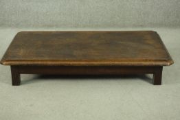 An elm low coffee table, of rectangular form with canted corners and a moulded edge, on square