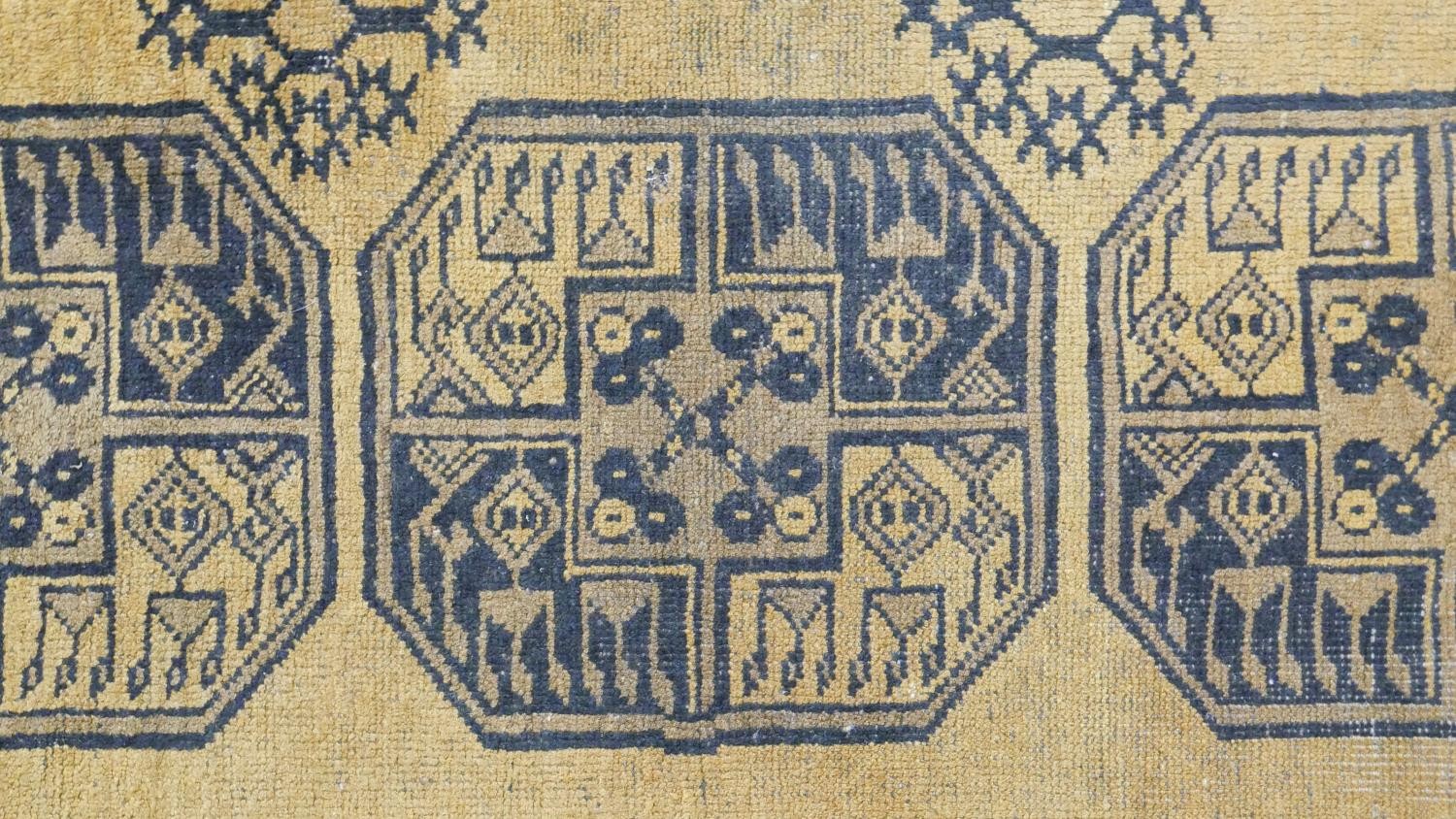 A hand made Afghan carpet with repeating gul medallions on a gold ground contained within multiple - Image 6 of 7