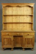 A Victorian style pine kneehole dresser with open plate rack above three short drawers over three